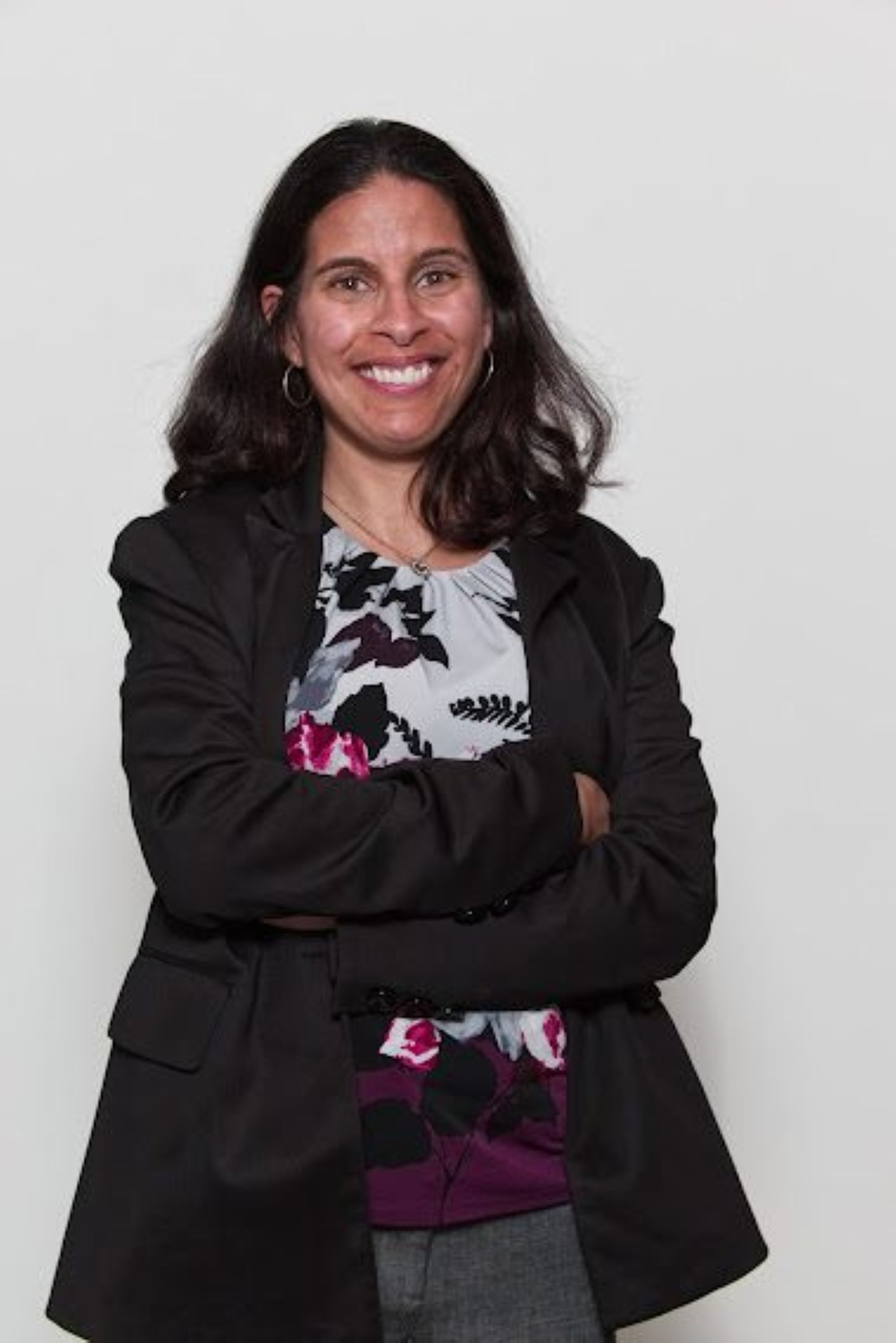 woman with black hair wearing blazer in powerful pose with arms crossedand thriving. 
